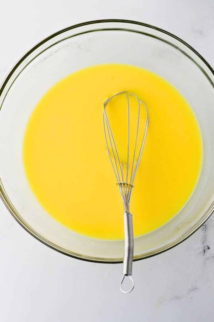 Milk and powdered milk being mixed in a glass bowl.