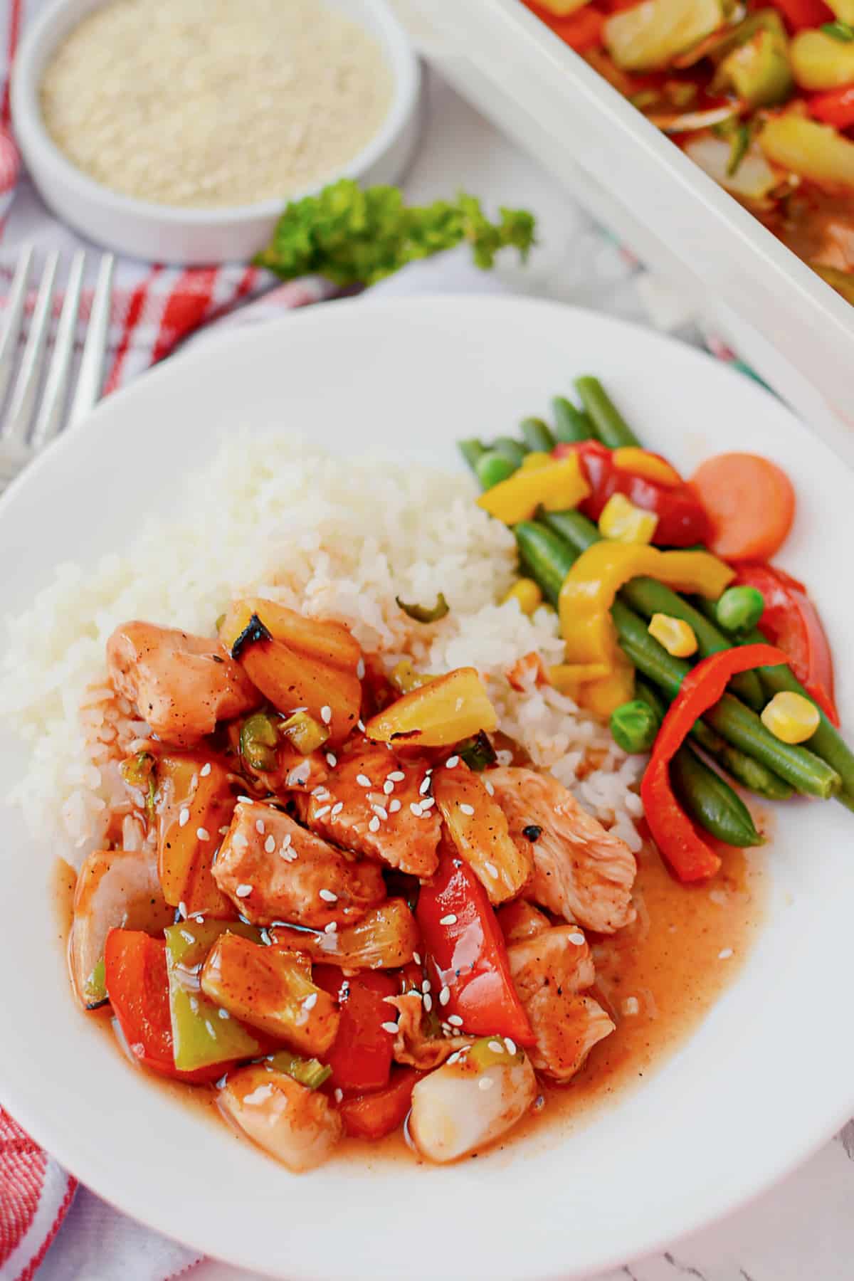 White plate full of rice, veggies, and bbq pineapple chicken.