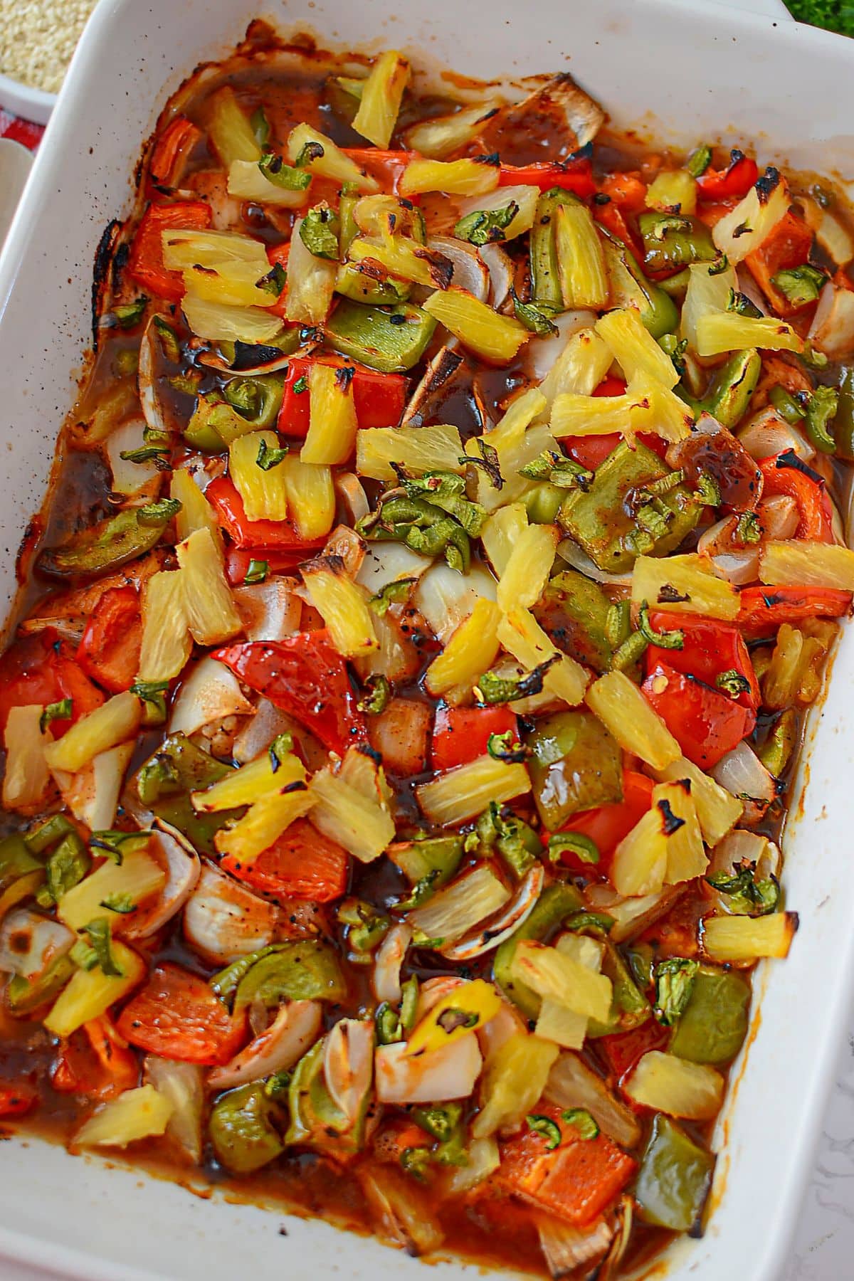 Cooked pineapple chicken in a white baking dish.
