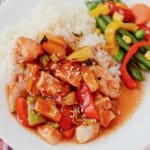 White plate full of rice, veggies, and bbq pineapple chicken.