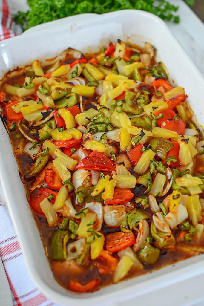Cooked pineapple chicken in a white baking dish.