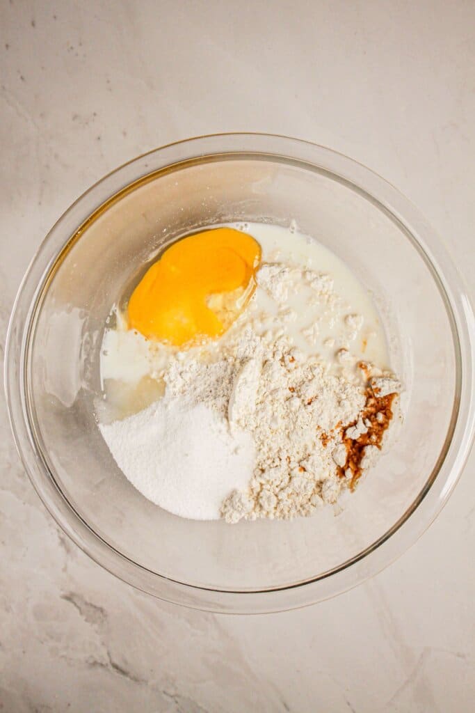 Dough ingredients being mixed in a large glass bowl.