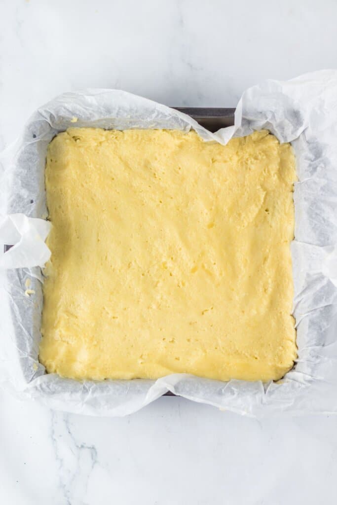Dough being pressed into a baking dish.