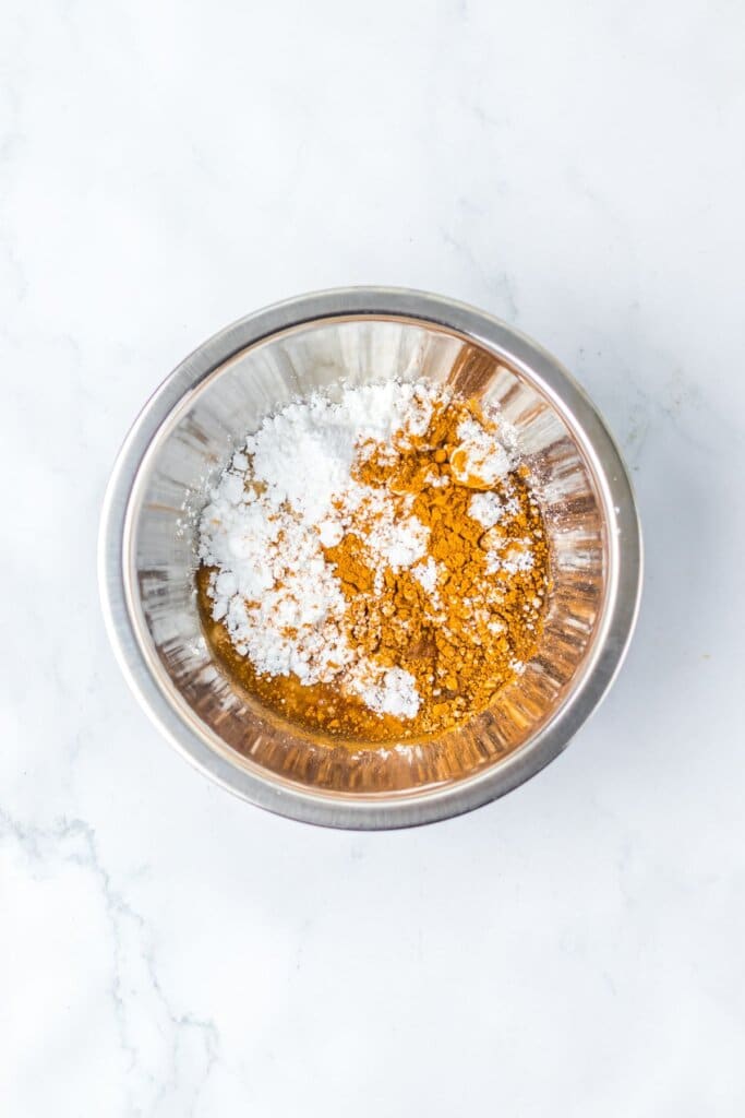 Frosting ingredients being mixed in a stainless steel bowl.