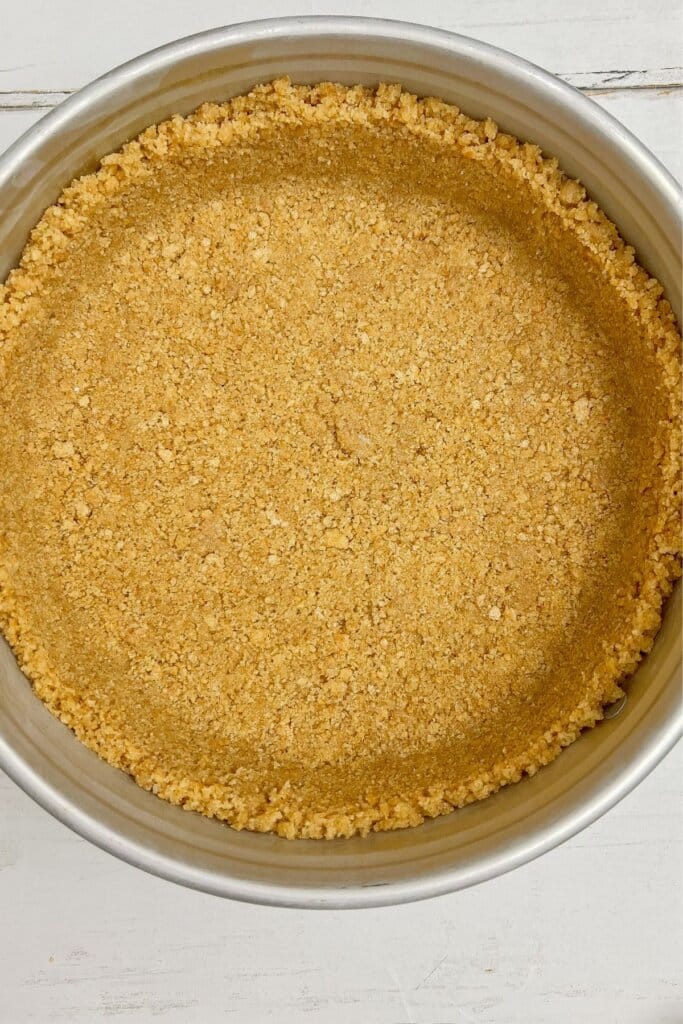 Crust being pressed into a springform pan.