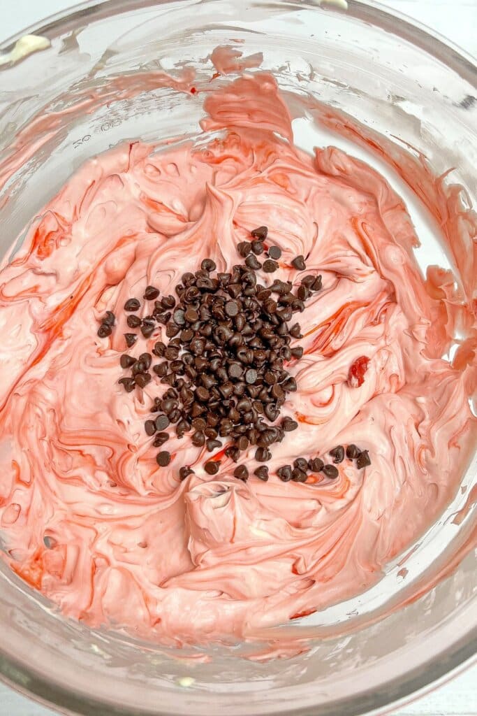 Chocolate being added to batter in a glass bowl.