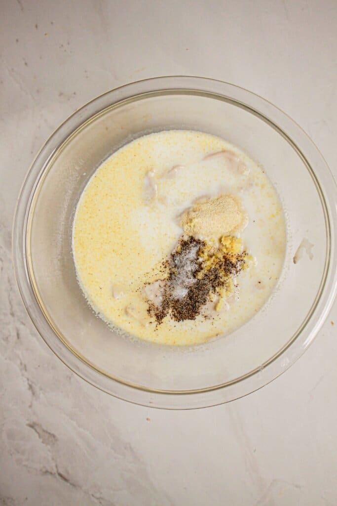 Cream sauce being mixed in a large glass bowl.