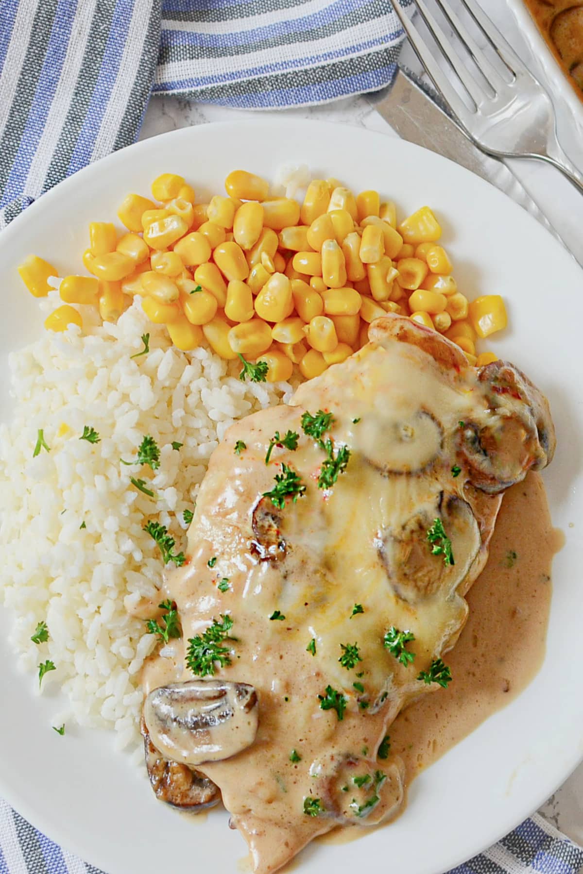White plate with chicken gloria, white rice, and corn.