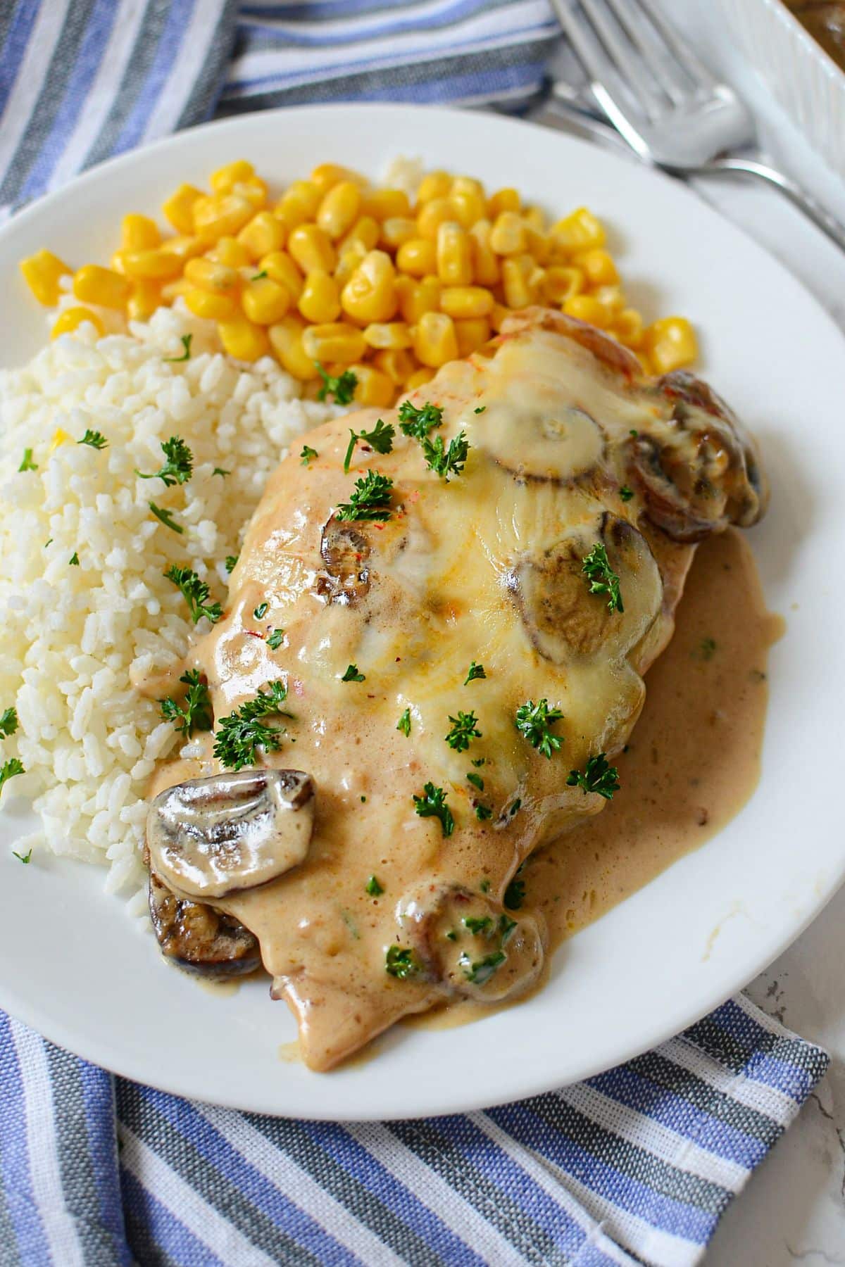White plate with chicken gloria, white rice, and corn.