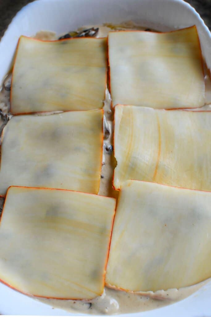 Cheese sliced on top of food in a white baking dish.