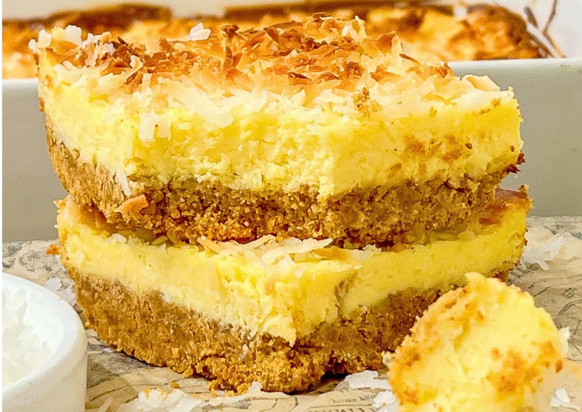 Two slices of coconut cream cheesecake bars stacked on top of each other.