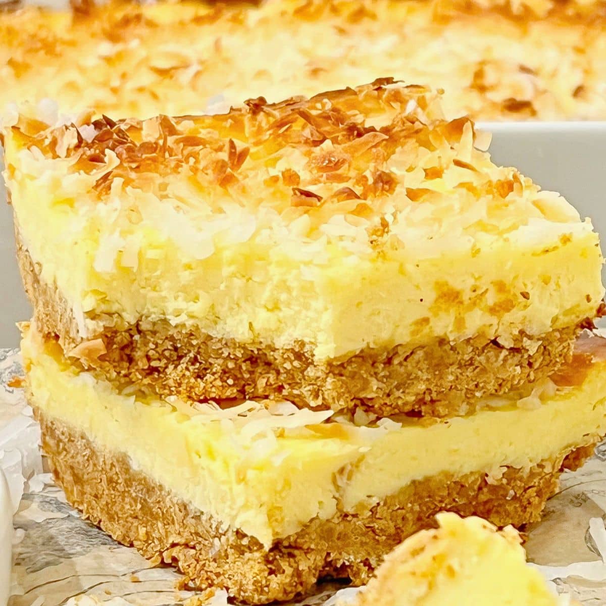 Two slices of coconut cream cheesecake bars stacked on top of each other.