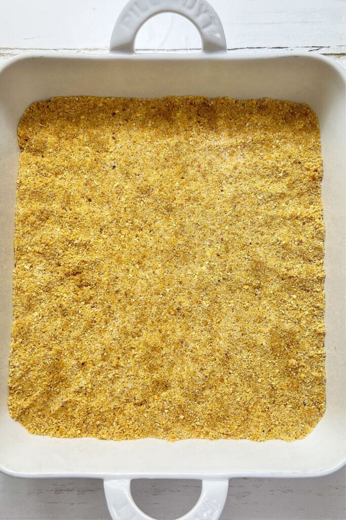 Crust being pressed into the bottom of a baking dish.