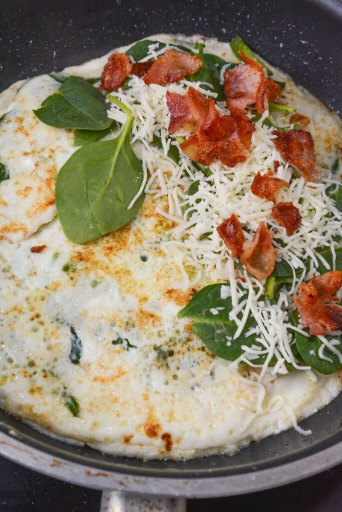 Spinach and bacon in a skillet.