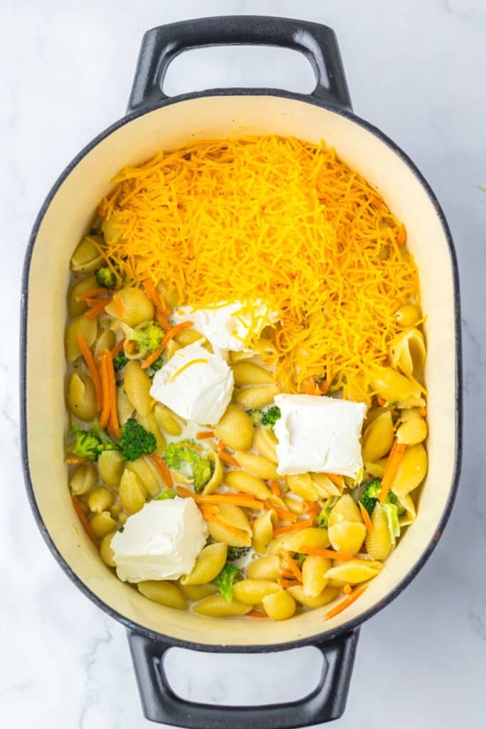 Cheese and cream cheese being added to a pot of ingredients. 