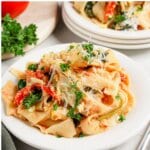 Pasta with Spinach and Tomatoes White plate full of pasta with spinach and tomatoes.
