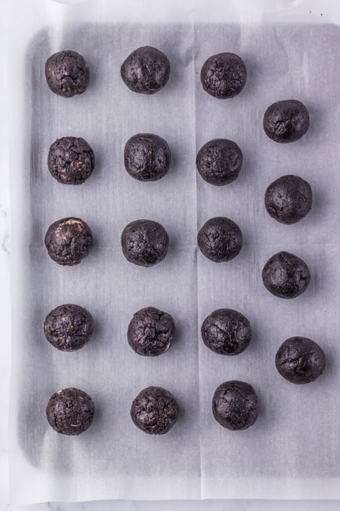 Chocolate balls on a parchment lined baking sheet.