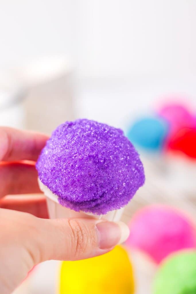 Rainbow snowcone oreo truffle held in a woman's hand.