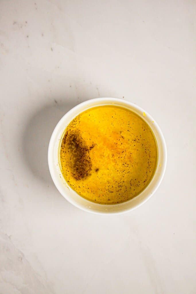 Dressing being mixed in a small white bowl.