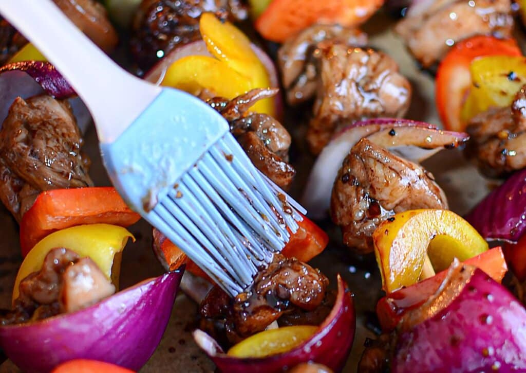 Marinade being brushed on skewers.