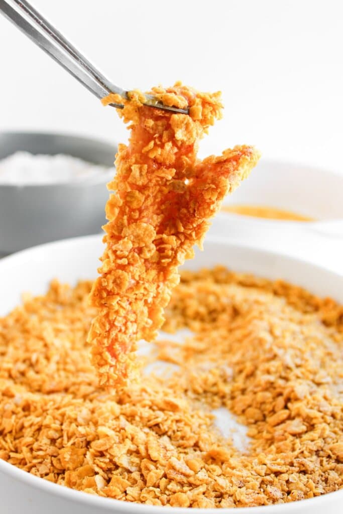 Pieces of meat being breaded in cornflakes.