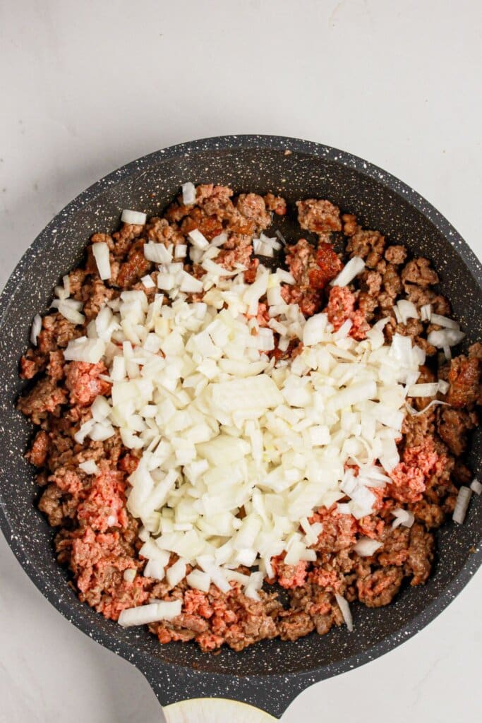 Meat and onions being cooked in a skillet.