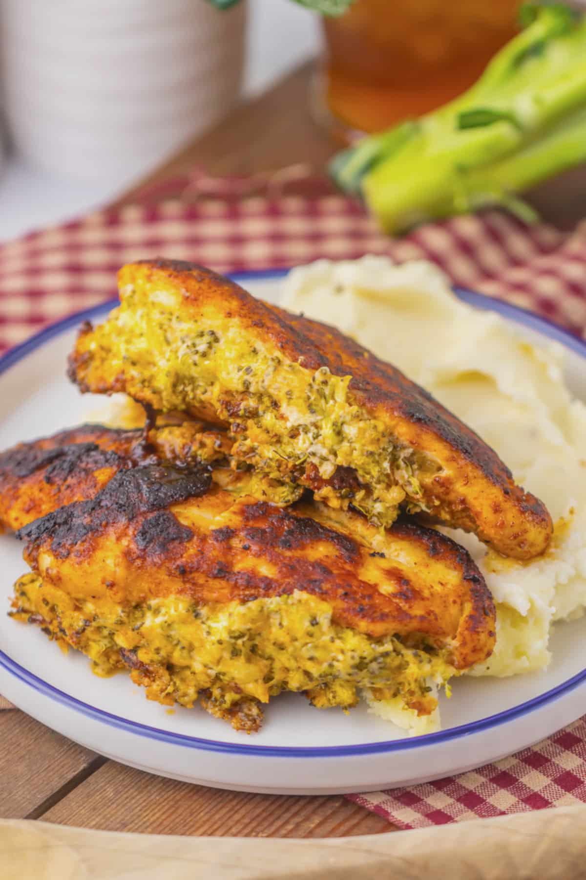 Broccoli stuffed chicken breasts on a plate with mashed potatoes.