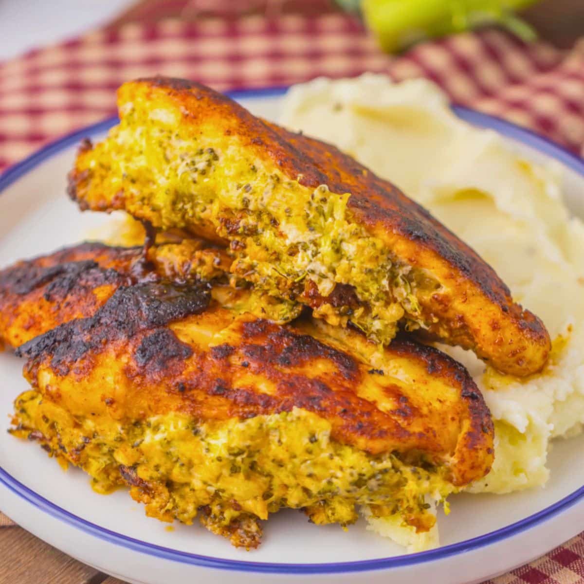 Broccoli stuffed chicken breasts on a plate with mashed potatoes.