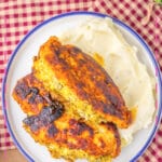 Broccoli stuffed chicken breasts on a plate with mashed potatoes.