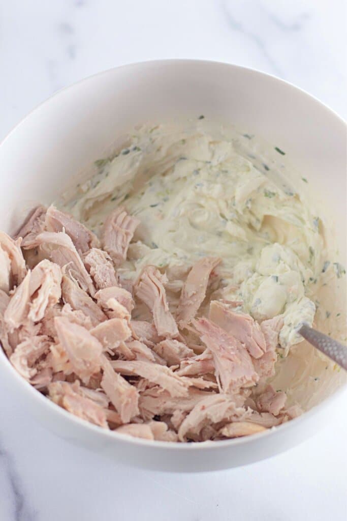 Meat and cream cheese being mixed together.