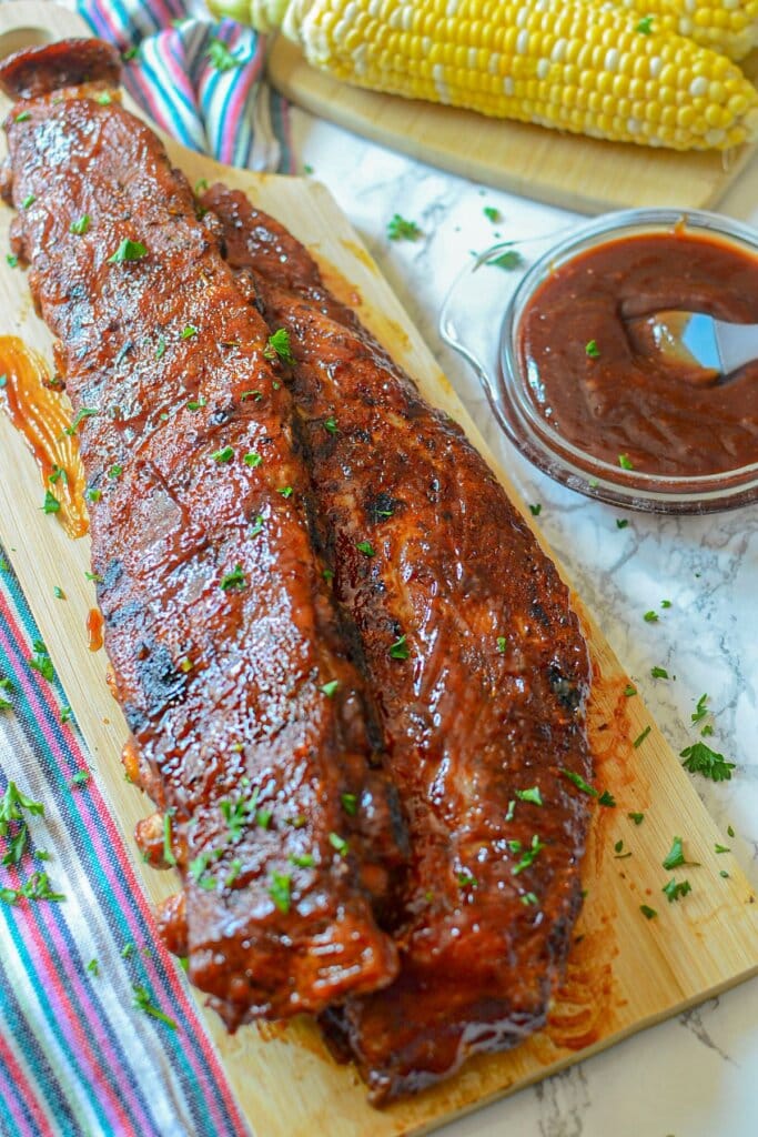 Two racks of ribs on a wooden cutting board.