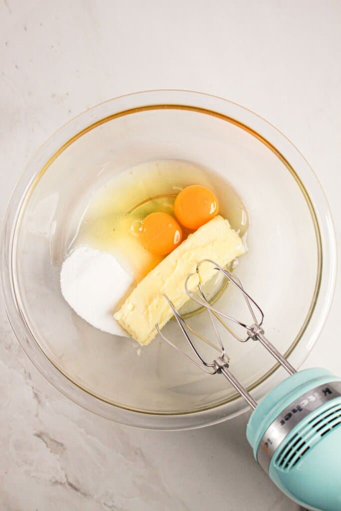 Eggs, butter, and sugar being mixed in a bowl.