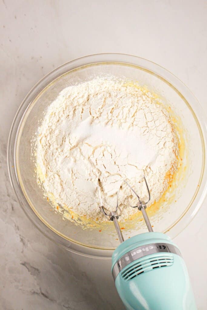 Flour being added to batter in a glass bowl.