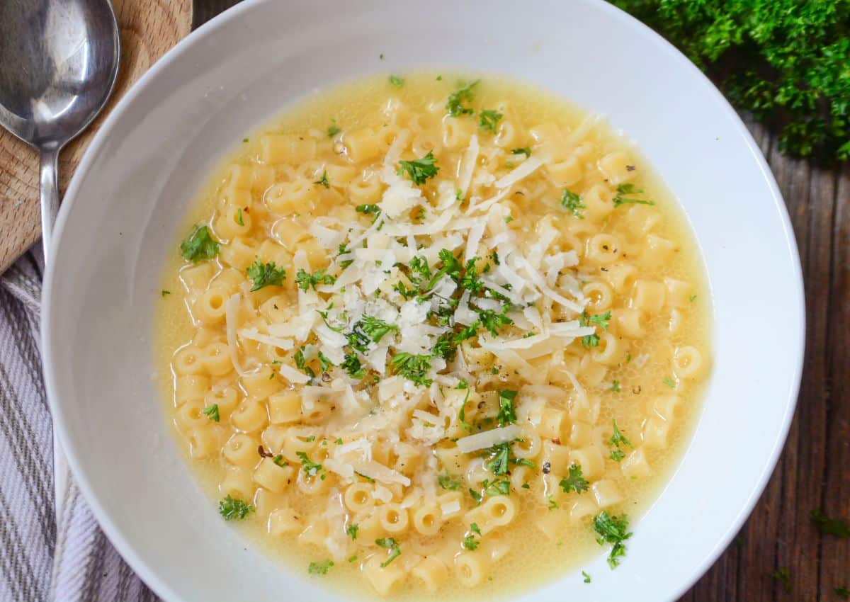 White bowl of parmesan pasta soup.