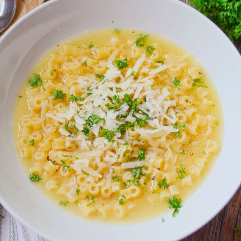 White bowl of parmesan pasta soup.