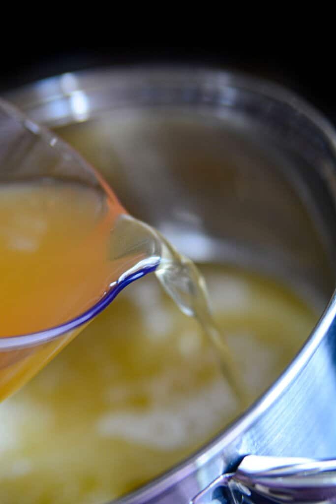 Broth being added to a pot.