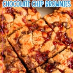 Peanut butter chocolate chip brownies topped with jam cut into squares.