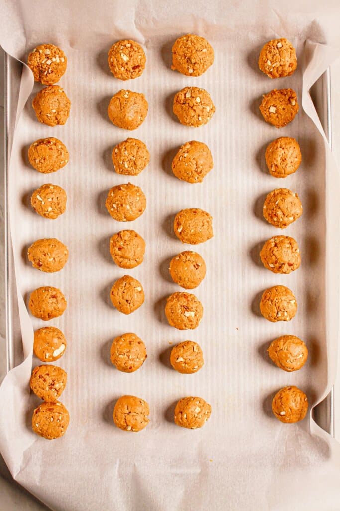 Peanut butter balls on a parchment lined baking sheet.