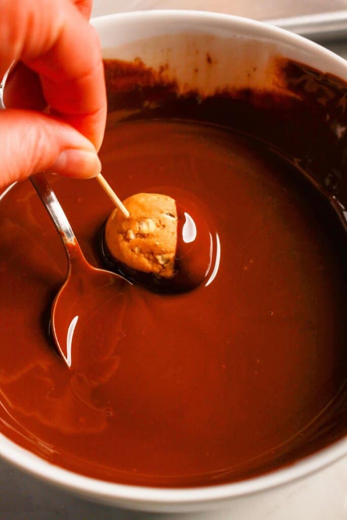 Peanut butter ball being dipped into chocolate.