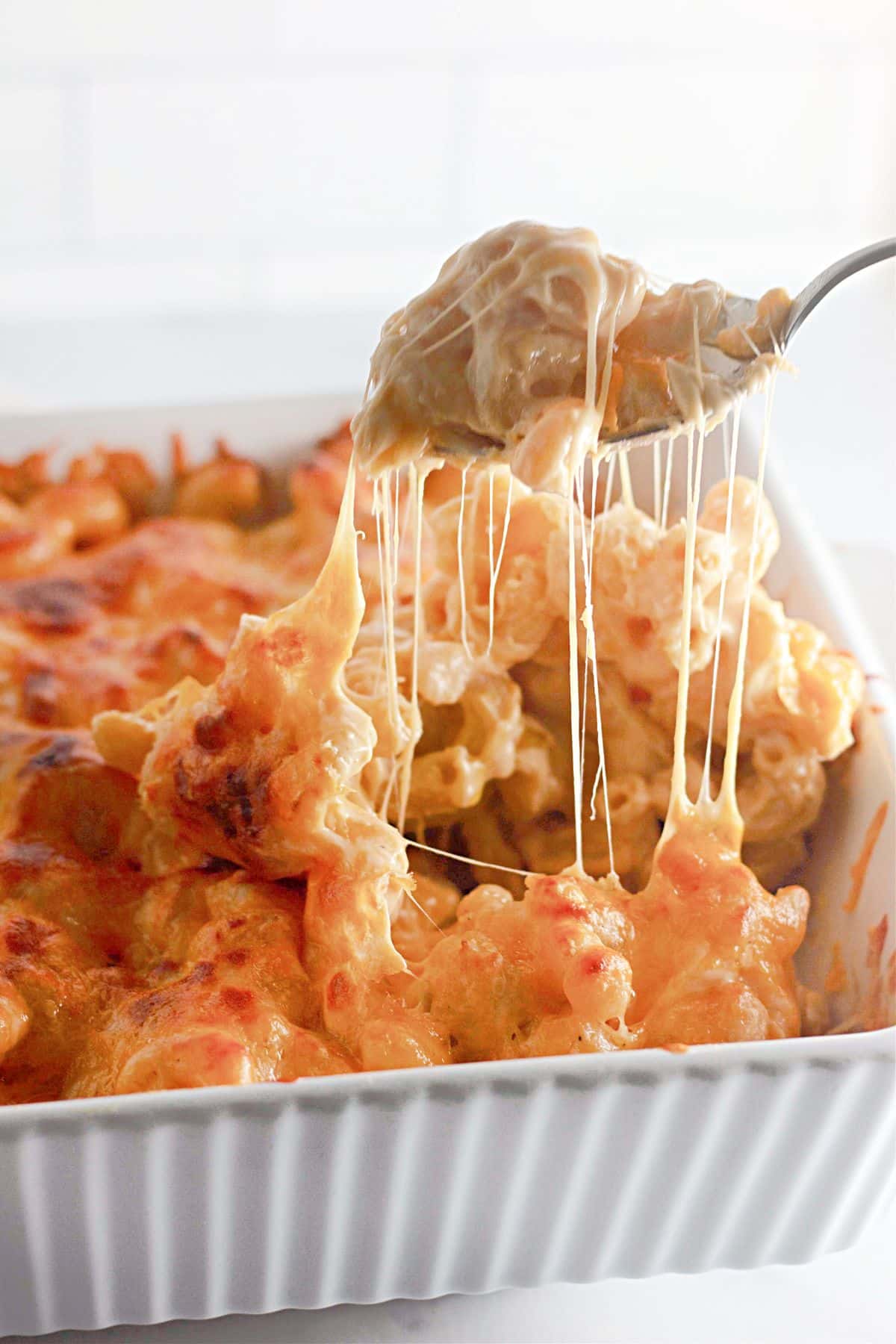 Spoonful of mac and cheese being removed from a casserole dish.