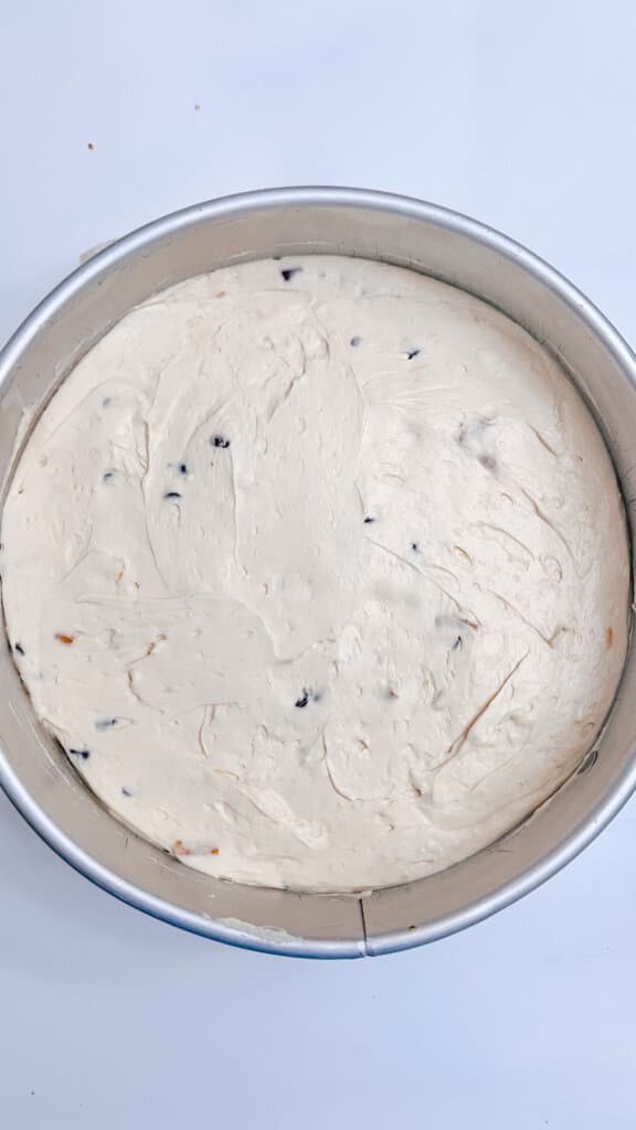 pouring the cheesecake batter on top of the crust in the pan.