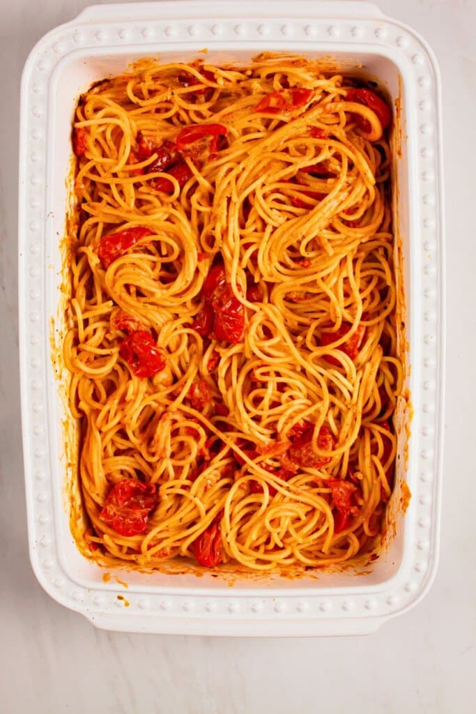 Noodles being added to baking dish.