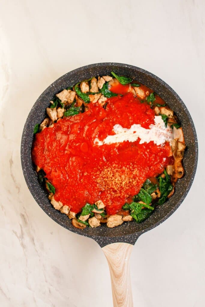 Marinara sauce being added to frying pan.