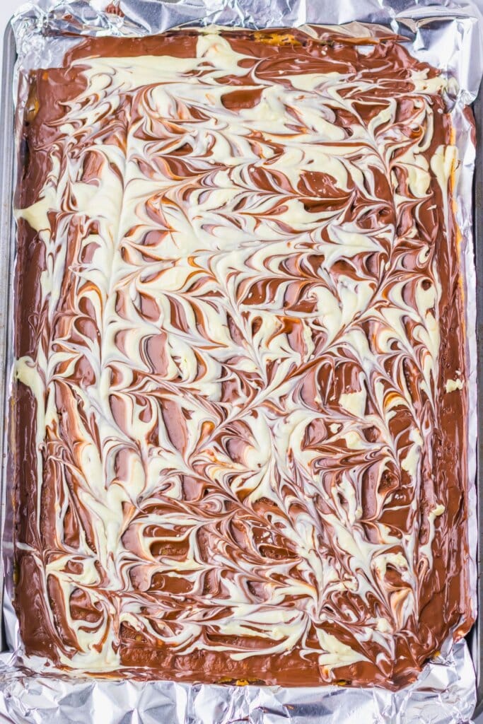 Chocolate being swirled on top of crackers.