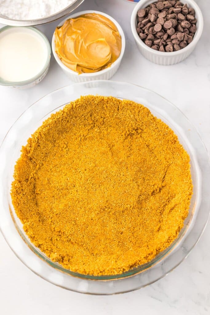 Crust being pressed into the bottom of a baking dish.