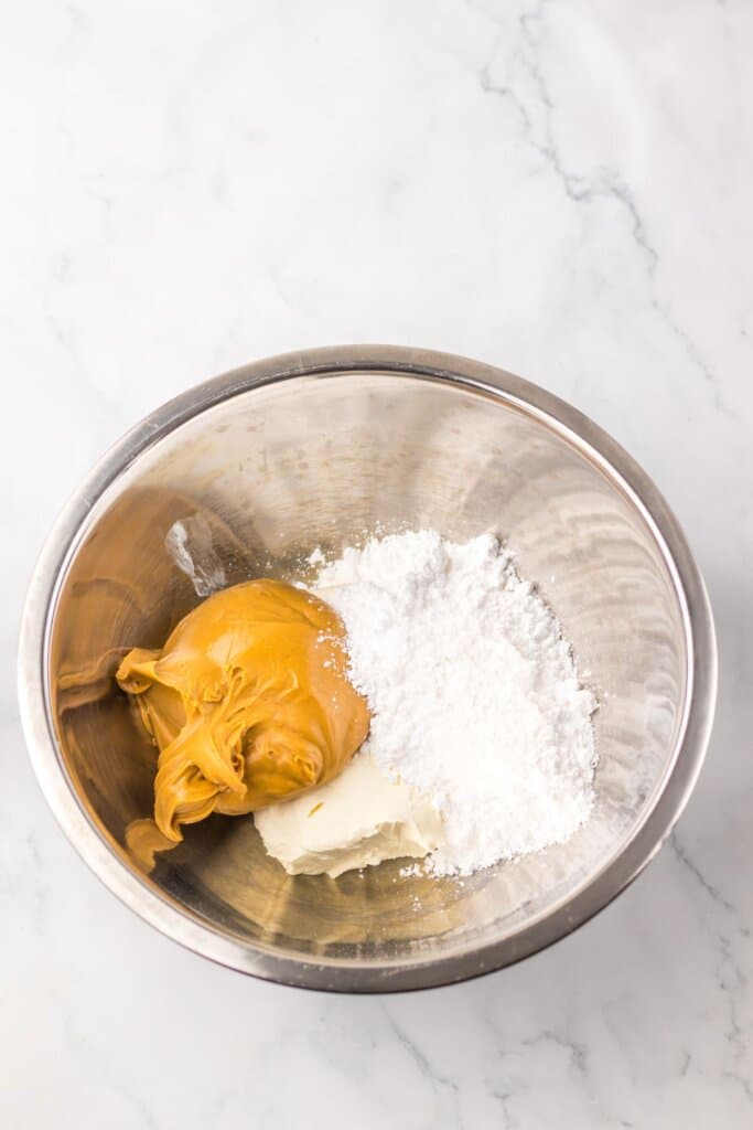 Peanut butter and powdered sugar being mixed together in a bowl.