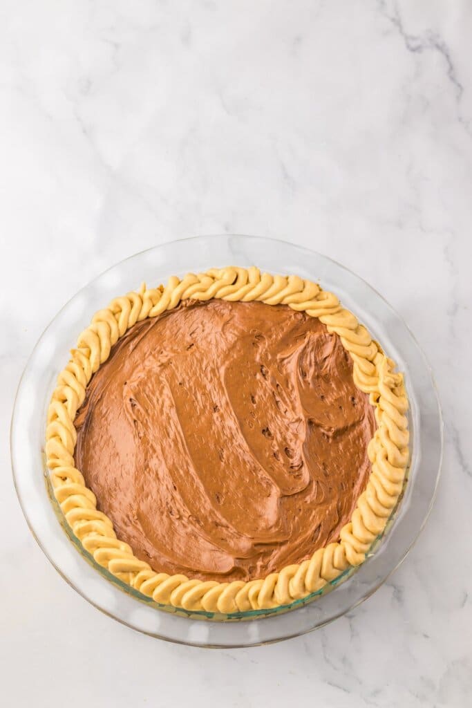 Chocolate being spread on top of dessert.