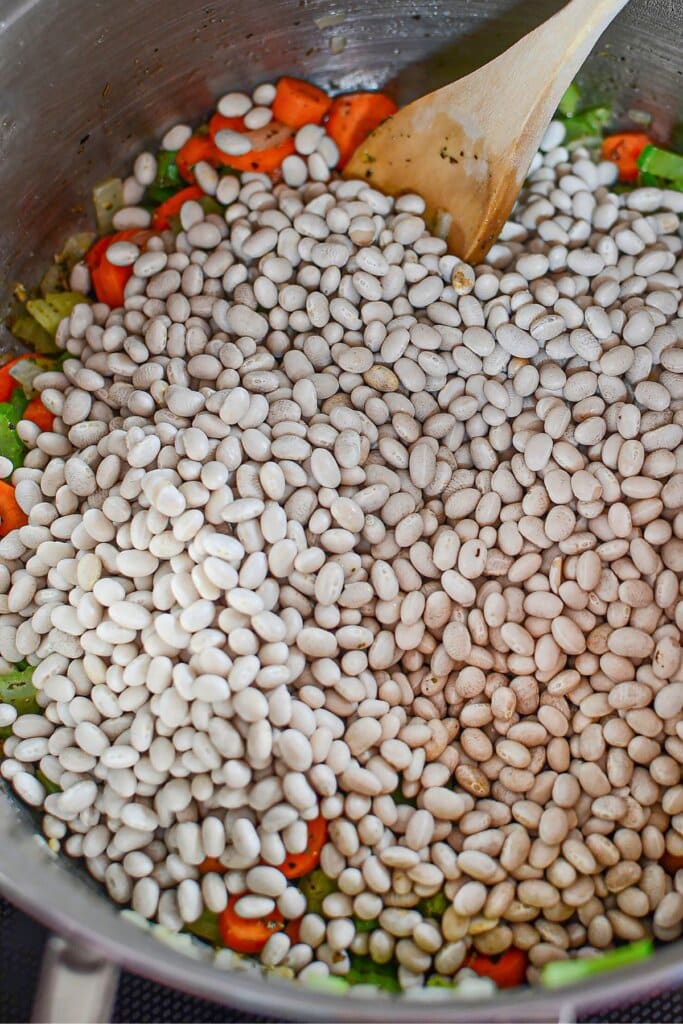 Beans being added to a pot on the stove.