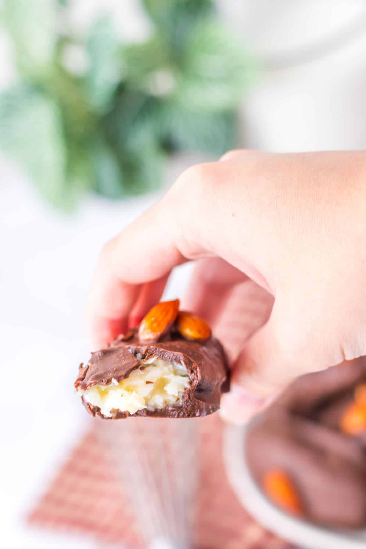 Almond joy broken in half held in a woman's hand.