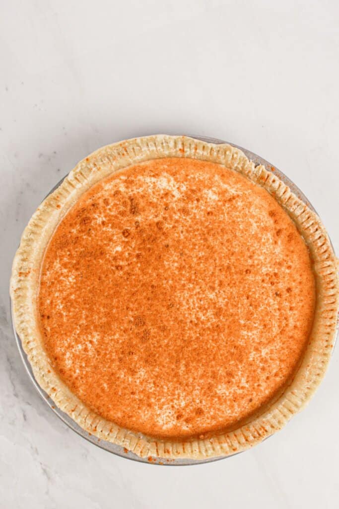 Cinnamon and nutmeg being sprinkled on top of filling.